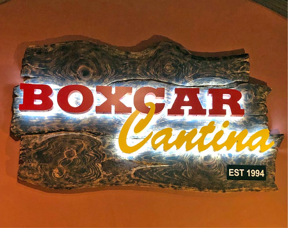 Boxcar Cantina custom signage includes dimensional halo lit letters on a piece of driftwood