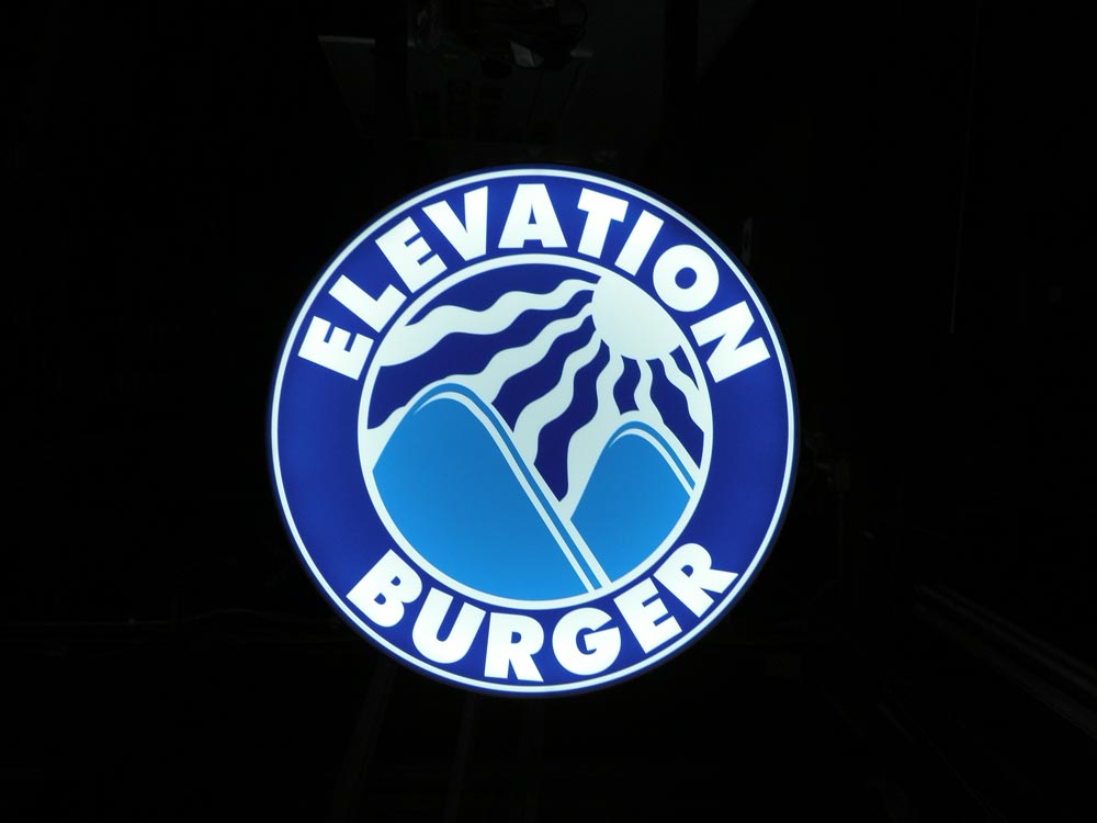Elevation Burger’s illuminated logo signage in complete darkness